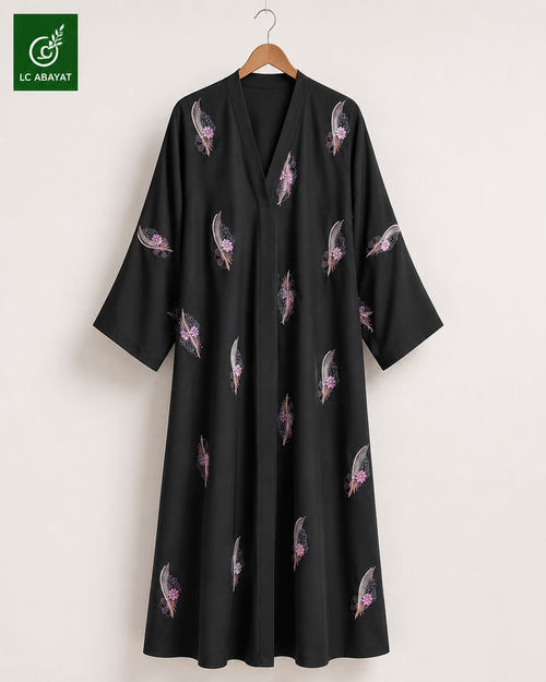 A black Abaya with wide full sleeves and a V-neckline, decorated with scattered pink and gray feather patterns, hanging on a wooden hanger against a light beige wall. The LC ABAYAT brand logo is visible in the top-left corner.