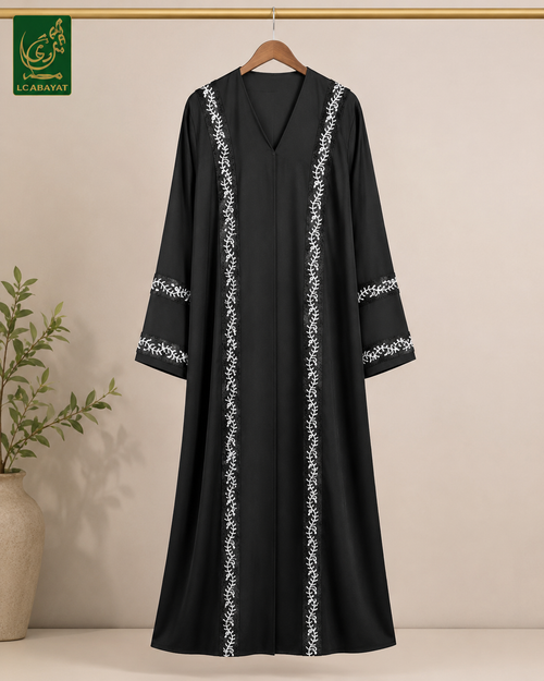 A black long abaya dress with white floral embroidery down the front and on the sleeves, hanging on a wooden hanger against a beige wall. The brand logo 'LC ABAYAT' is visible in the top left corner.