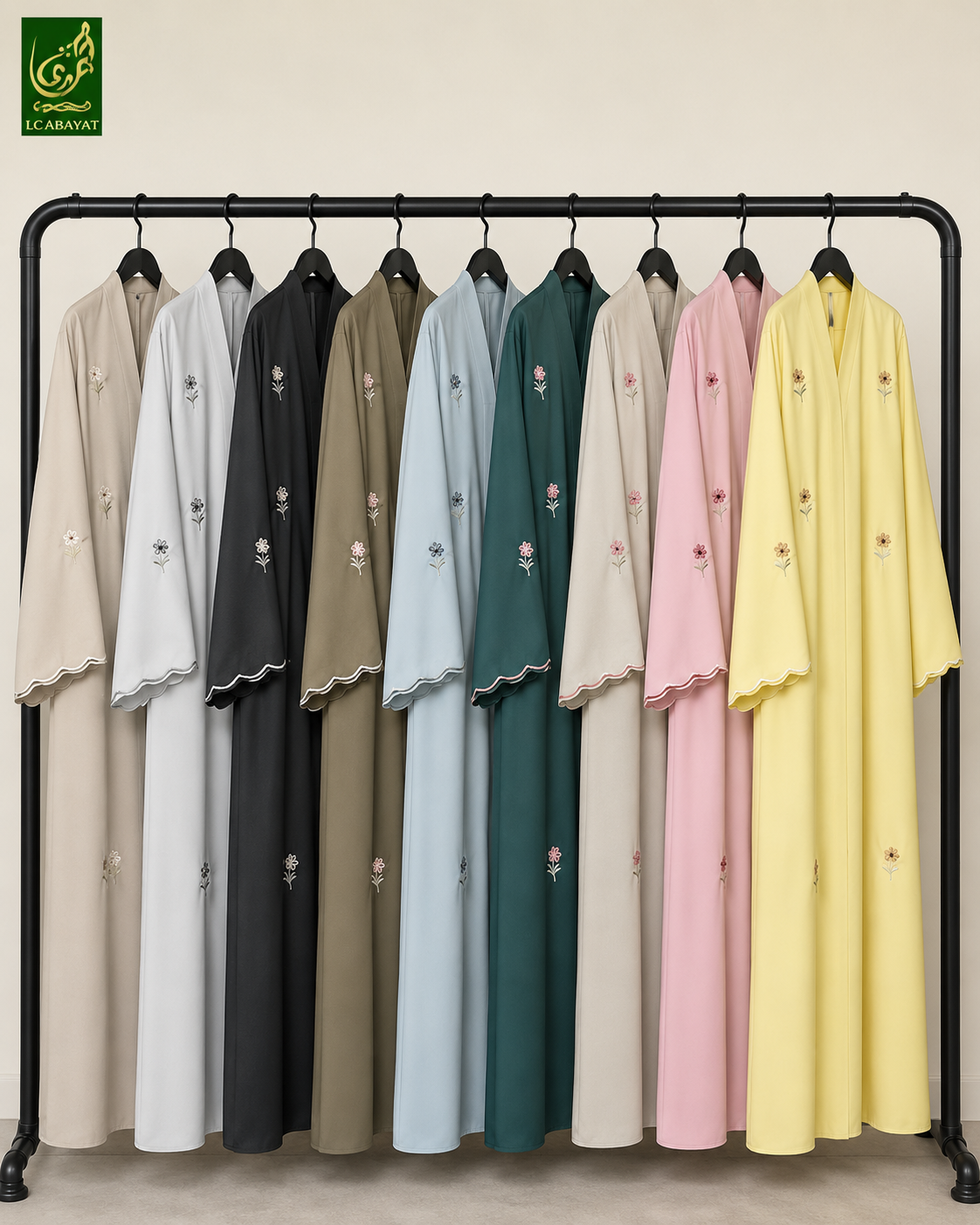 A black clothing rack displaying a row of long-sleeved abayas in multiple colors, including beige, white, charcoal, taupe, light blue, forest green, cream, pink, and pale yellow. Each robe features small floral embroidery on the front and a scalloped hem.