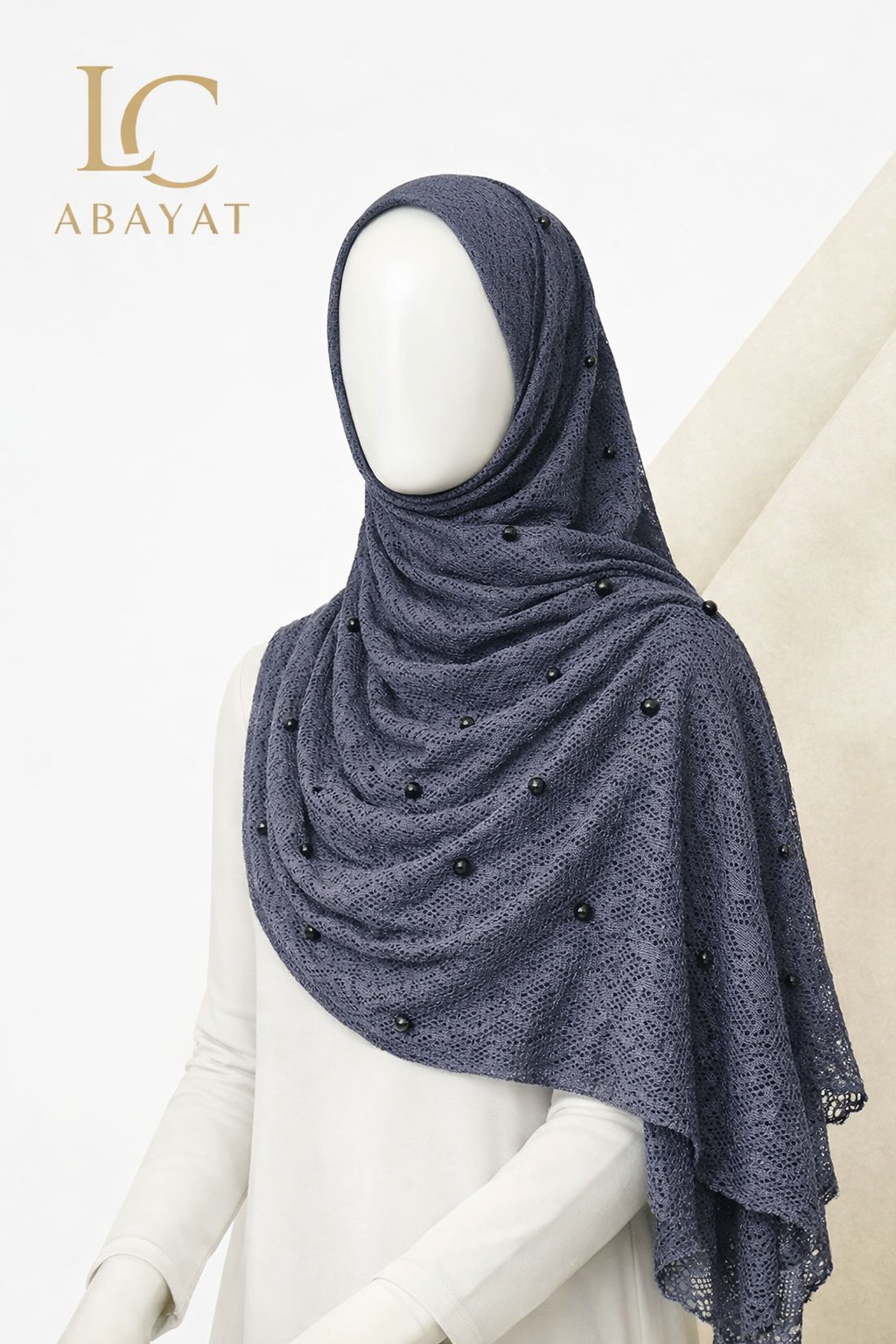 A dark slate blue-gray lace hijab with small black bead embellishments, displayed on a white mannequin. The LC Abayat brand logo is visible in the top left corner.