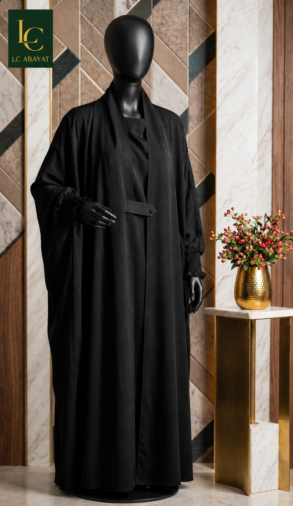 A black long jilbab displayed on a black mannequin, set against a luxury interior background with marble and wood paneling, a side table with flowers, and the LC ABAYAT logo in the top left corner.