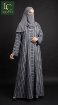 A woman modeling a long gray abaya dress with a vertical textured stripe pattern, paired with a matching gray hijab and face veil, set against a dark studio background. The 'LC ABAYAT' brand logo is visible in the top-left corner.