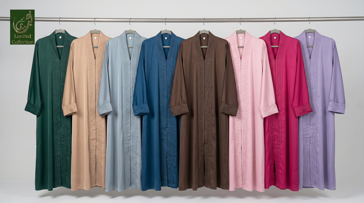 Eight long, loose-fitting ctc stonework abayas hang on a metal rod against a plain light gray wall. The robes come in multiple solid colors: dark green, beige, light blue, medium blue, brown, pink, magenta, and lavender.