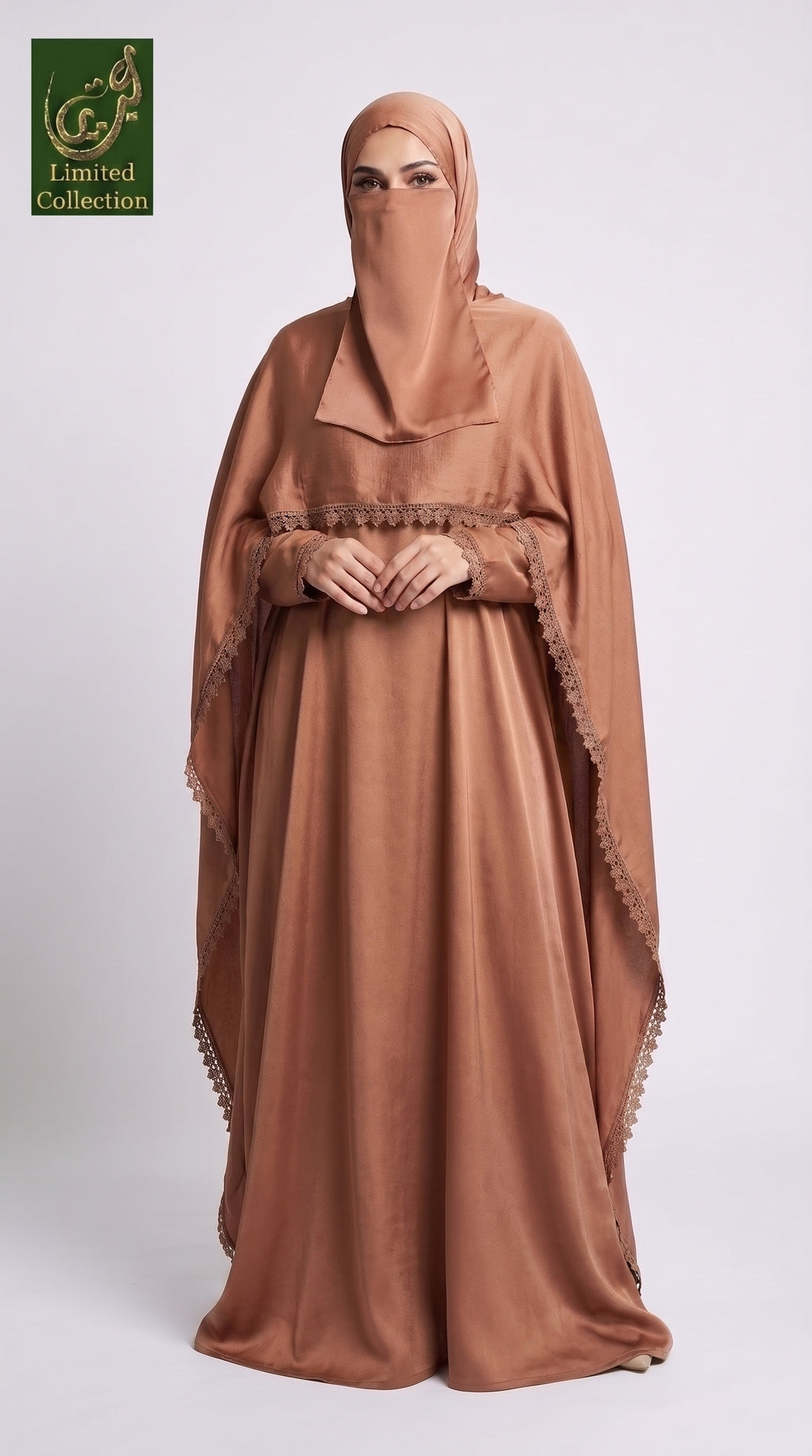 A woman wearing a flowing tan cape style maxi abaya with a matching face veil and headscarf, standing against a light gray studio background. A green 'Abayat Limited Collection' logo appears in the top-left corner.