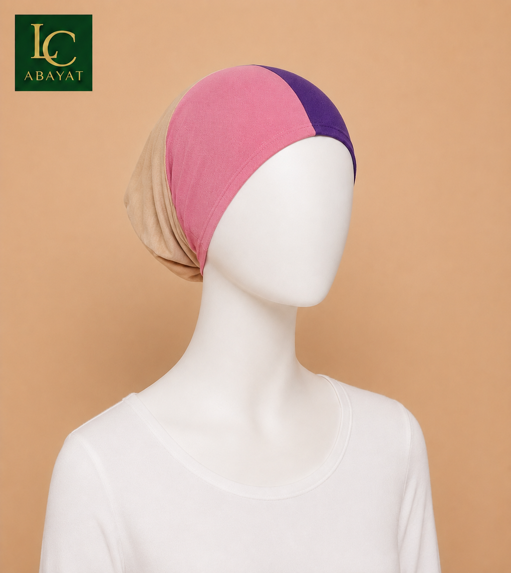 A color-blocked headscarf displayed on a white mannequin torso against a solid beige background. The headscarf features three color panels: a light beige side, a pink center, and a dark purple side.
