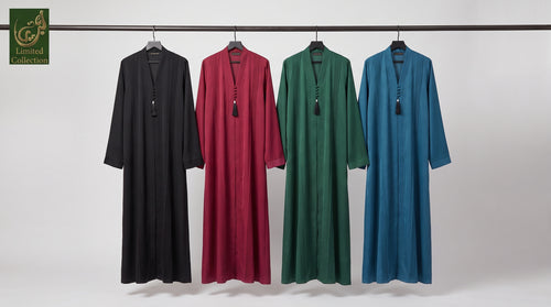 Four long flowing Dubai Style Pleated Maxi Abaya With Tassel Button in Premium Romantic Nida fabric  hanging on a black rail against a light gray studio background. From left to right, the colors are black, deep burgundy, forest green, and medium blue.
