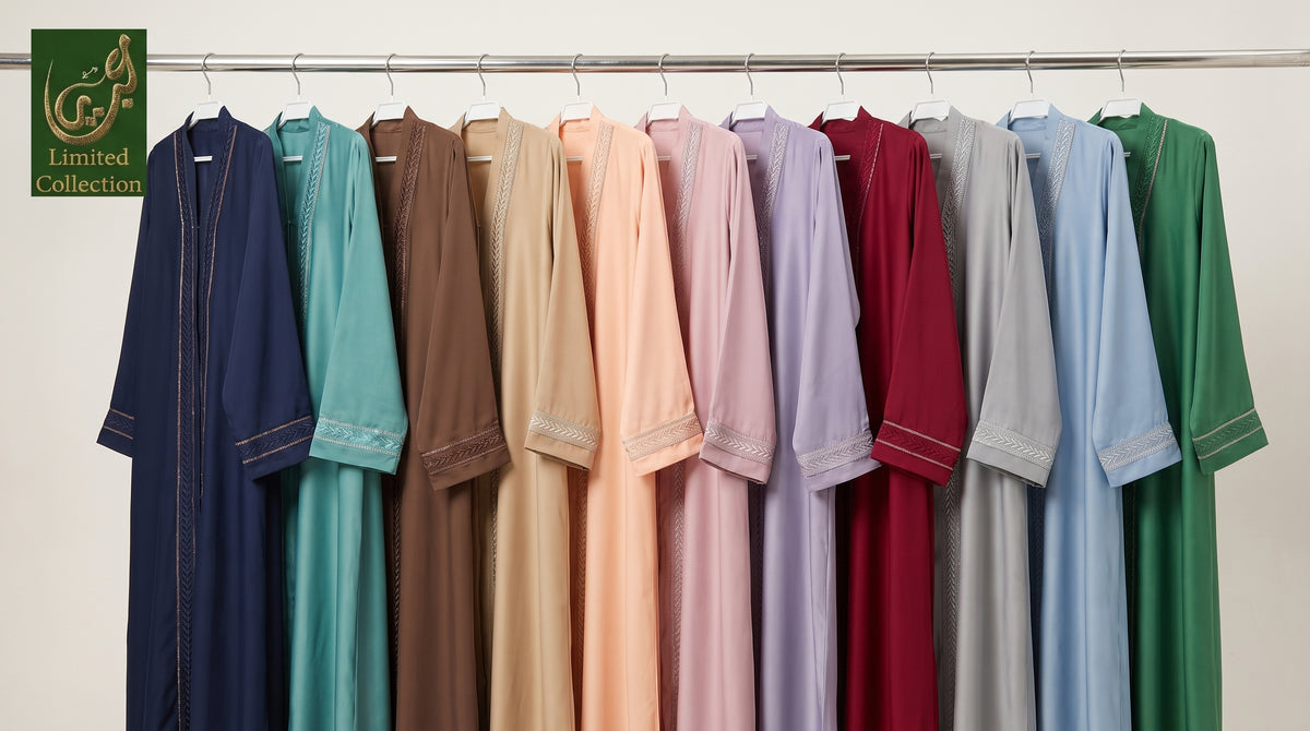 A row of long, loose-fitting front open abayas hanging on a metal rack against a plain light background. The garments come in multiple colors including navy, teal, brown, peach, pink, lavender, burgundy, light gray, sky blue, and green.