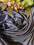 A draped piece of dark slate blue fabric with a subtle sheen, styled with artificial pink flowers and green leaves at the top.