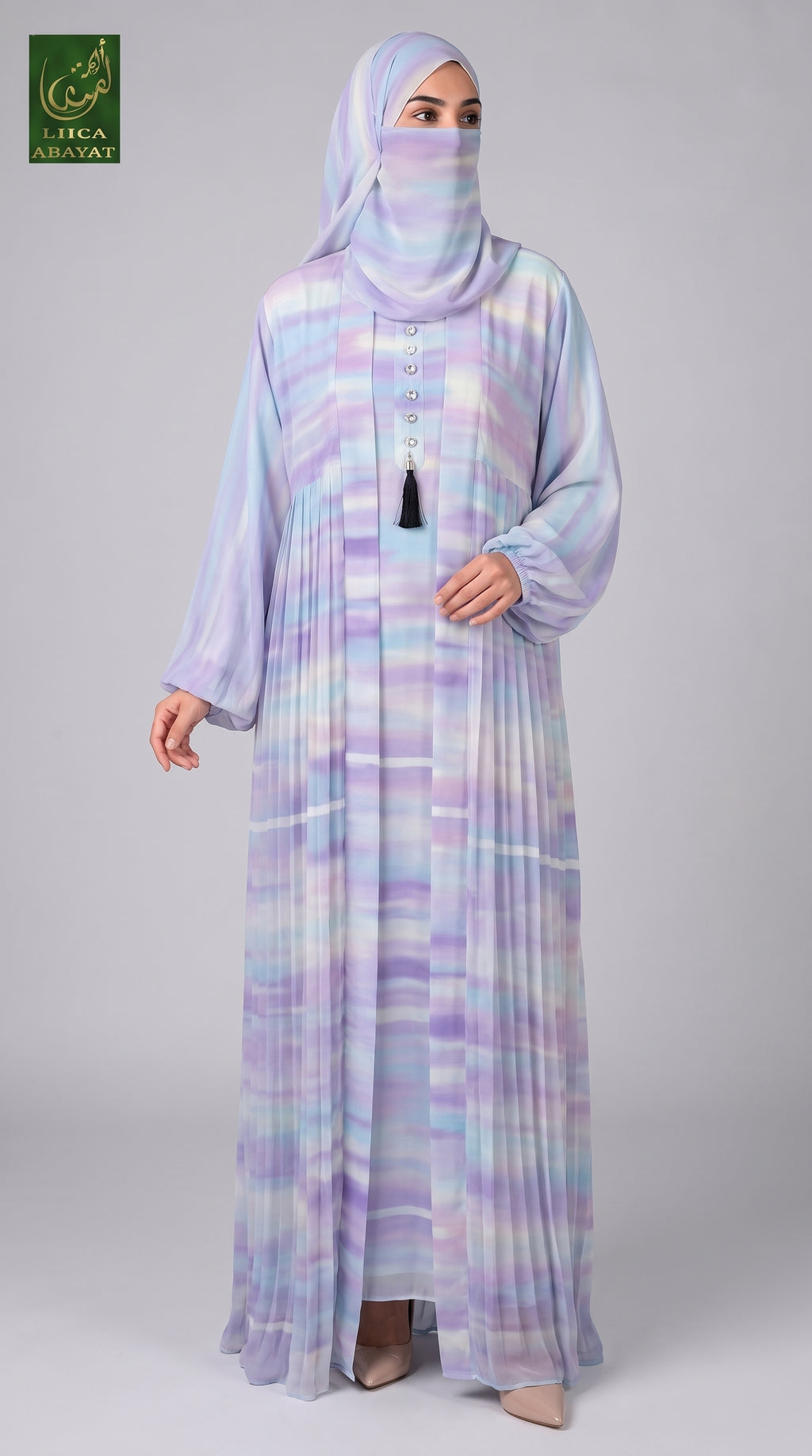 A woman modeling a long, flowing Cotton Candy Tie-Dye Front-open Kimono Abaya 2pcs set with a matching hijab and face covering. The garment has a pastel tie-dye pattern in lavender, purple, blue, and white.