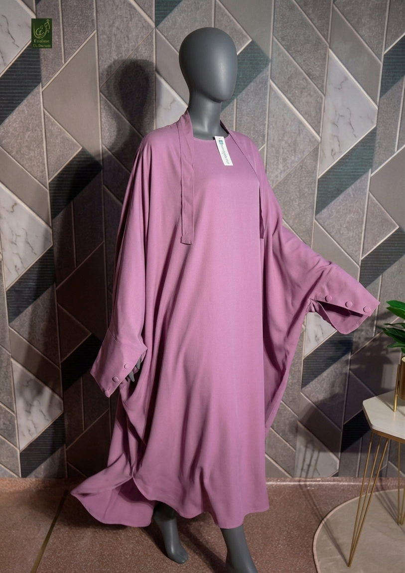 A mauve-pink Jilbab displayed on a black mannequin, set against a geometric tiled wall.