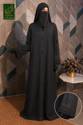 A woman wearing a full-length black abaya with a matching black face veil and black gloves, standing against a geometric patterned wall. The image includes a circular inset showing embroidered details on the sleeve and a green 'Limited Collection' logo in the top left corner.
