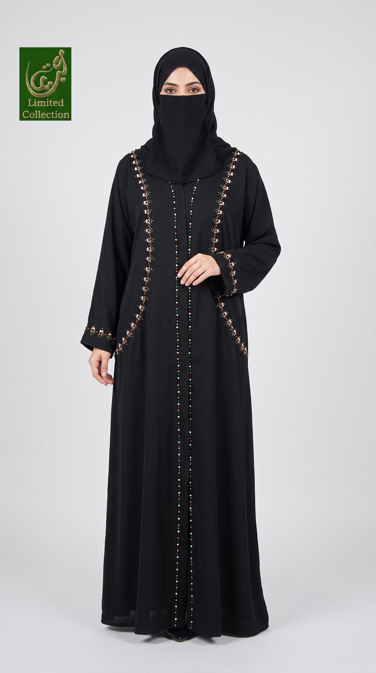 A woman wearing a long black abaya with gold decorative trim and a matching black face covering, standing against a light gray studio background. A green 'Gourmet Collection' logo appears in the top-left corner.