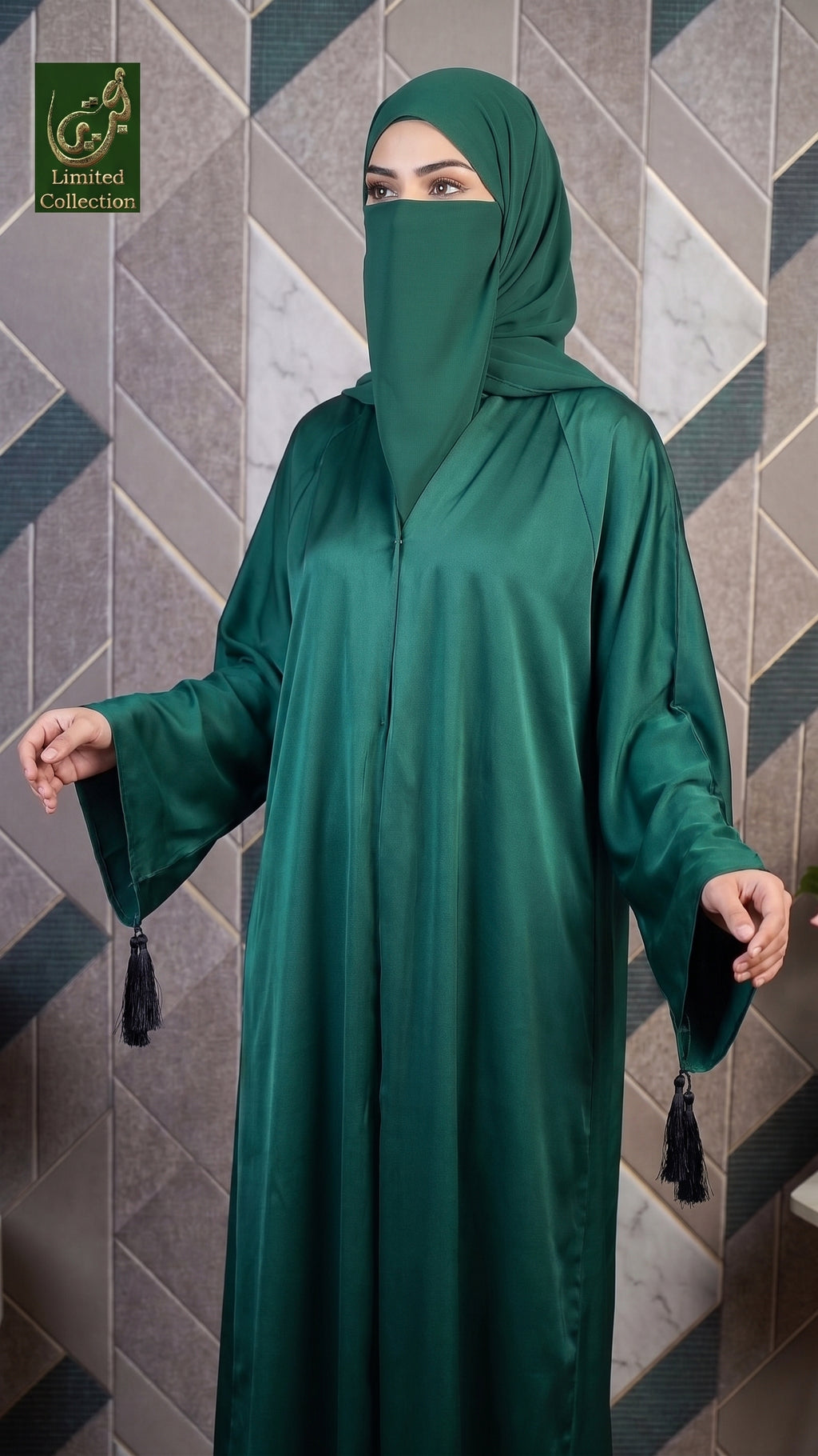 A woman wearing a dark green abaya and matching hijab stands against a geometric tiled wall. The abaya has wide sleeves with tassel details at the cuffs, and a front button opening is visible.