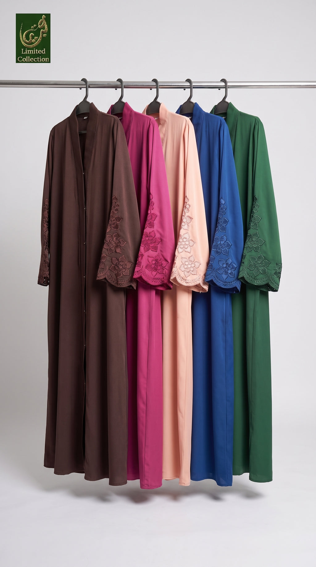 Five long flowing front-open stonework embroidery abayas in brown, magenta, peach, blue, and green hang on a metal rack against a light gray studio background. Each dress has embroidered lace sleeves and a matching embroidered collar.