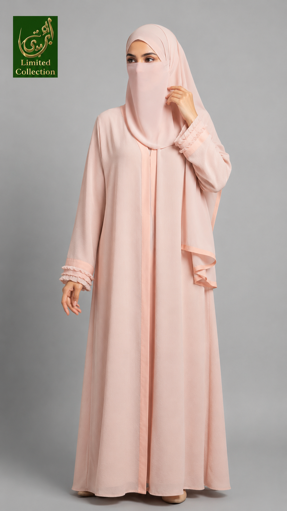 A woman modeling a light pink modest outfit consisting of a long abaya with lace-trimmed cuffs and a matching hijab, shown against a plain gray studio background. A green 'Abayat Limited Collection' logo appears in the top-left corner.
