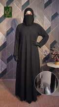 A woman modeling a long black Front-Closed Feather Cuff Maxi abaya with a matching black face covering and gloves, standing against a geometric patterned wall. A circular inset at the bottom right shows a close-up of the sleeve cuff detail.