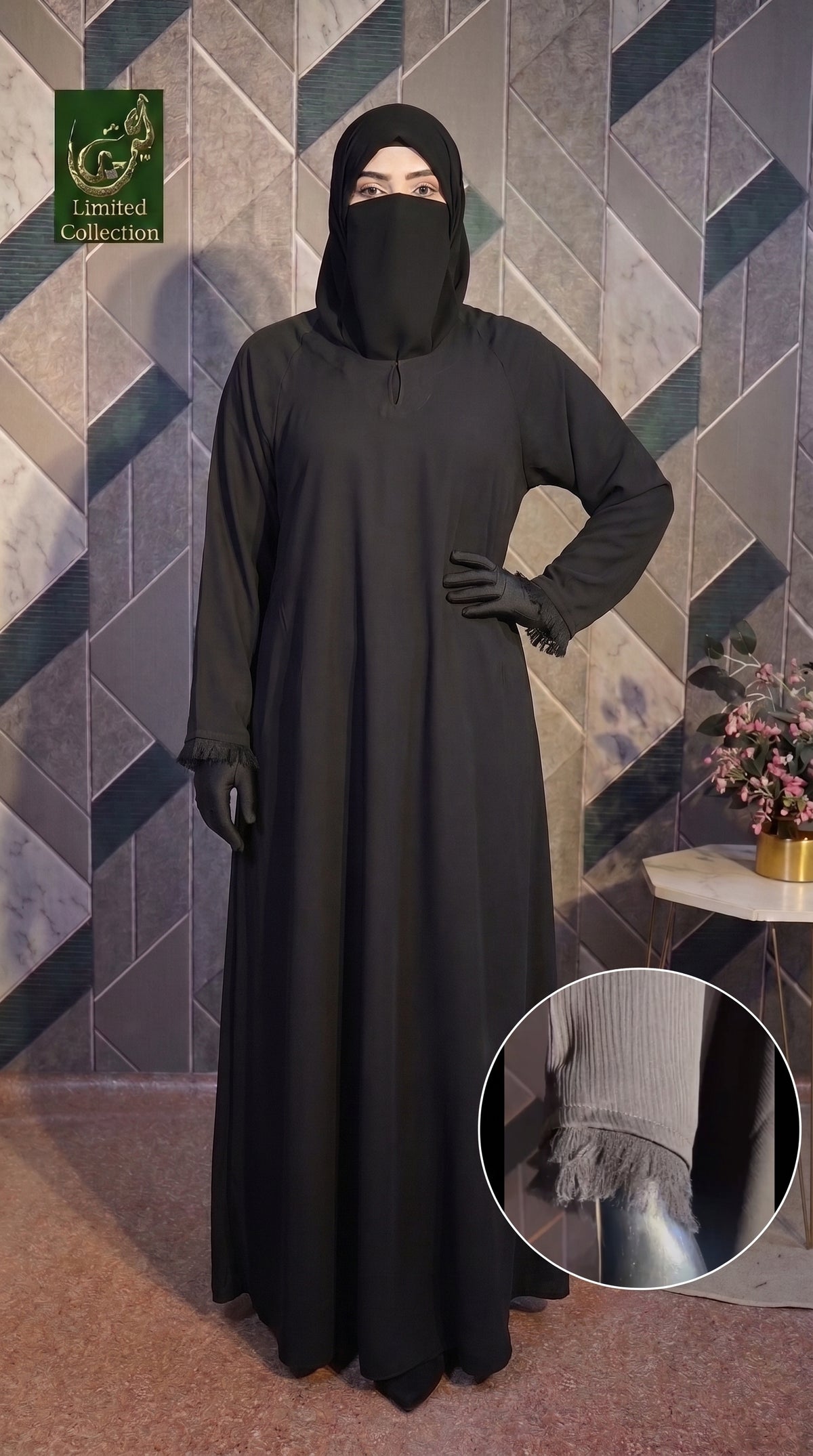 A woman modeling a long black Front-Closed Feather Cuff Maxi abaya with a matching black face covering and gloves, standing against a geometric patterned wall. A circular inset at the bottom right shows a close-up of the sleeve cuff detail.