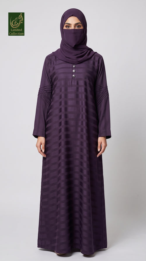 A woman wearing a long, floor-length dark purple abaya with a matching headscarf and face veil, standing against a light gray studio background. The abaya has a subtle horizontal striped texture and a buttoned neckline.