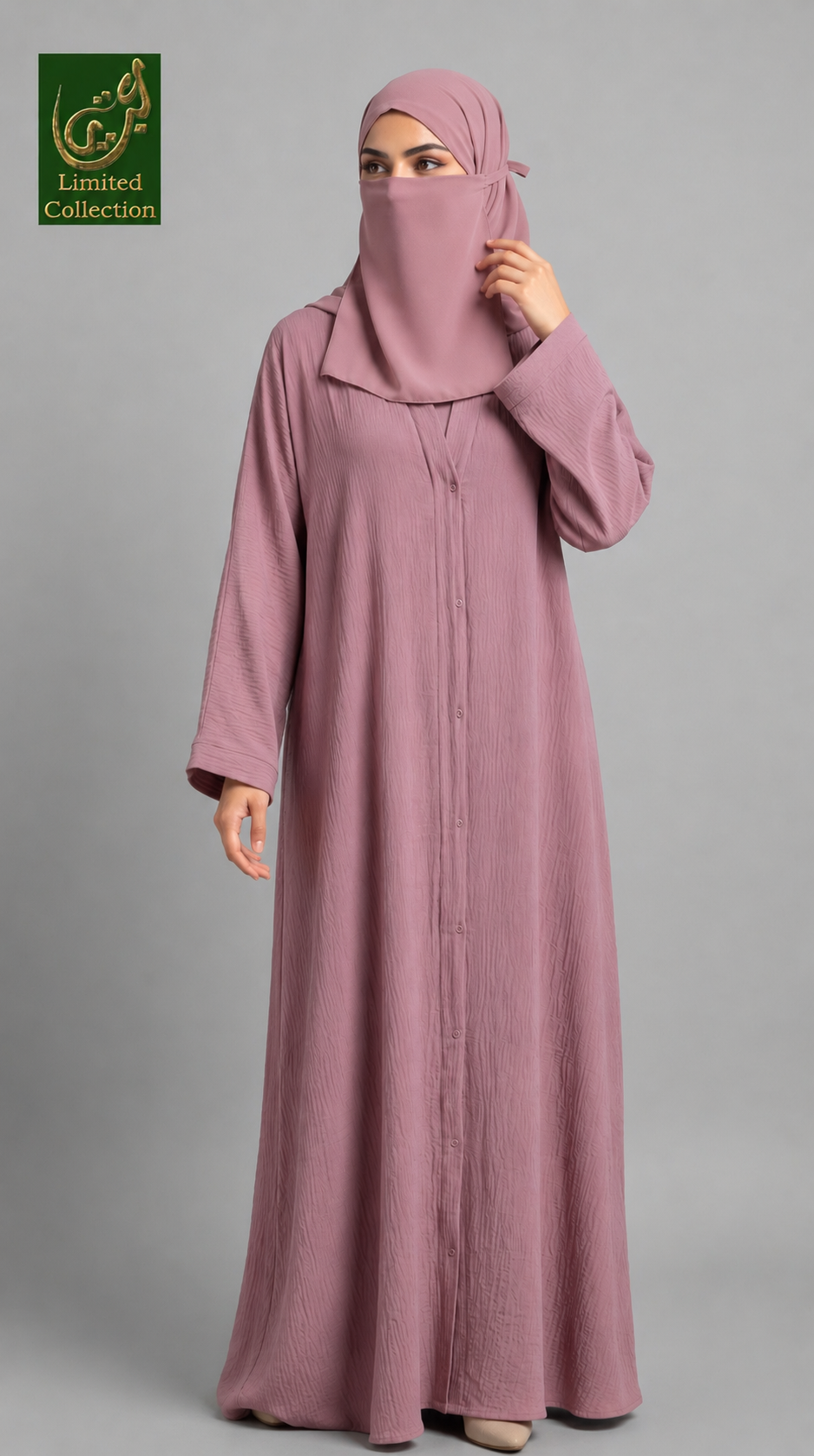 A woman wearing a long dusty pink abaya with a matching hijab and face veil, standing against a solid gray studio background. A green 'Limited Collection' logo is visible in the top-left corner.