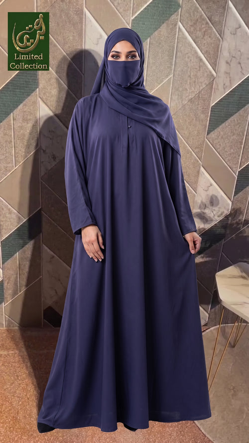 A woman wearing a long navy abaya with a matching hijab and face veil, standing in front of a geometric tiled wall. A logo for 'Adele Limited Collection' is visible in the top left corner.