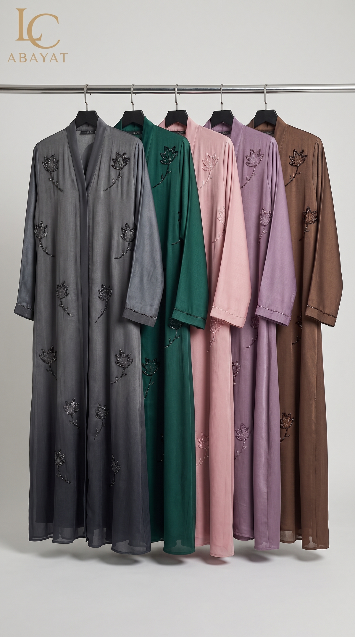 Five long open-front abaya robes hang on a metal rack against a light gray studio background. The abayas are shown in different colors: dark gray, emerald green, blush pink, lavender, and brown, each with matching embroidered floral motifs.