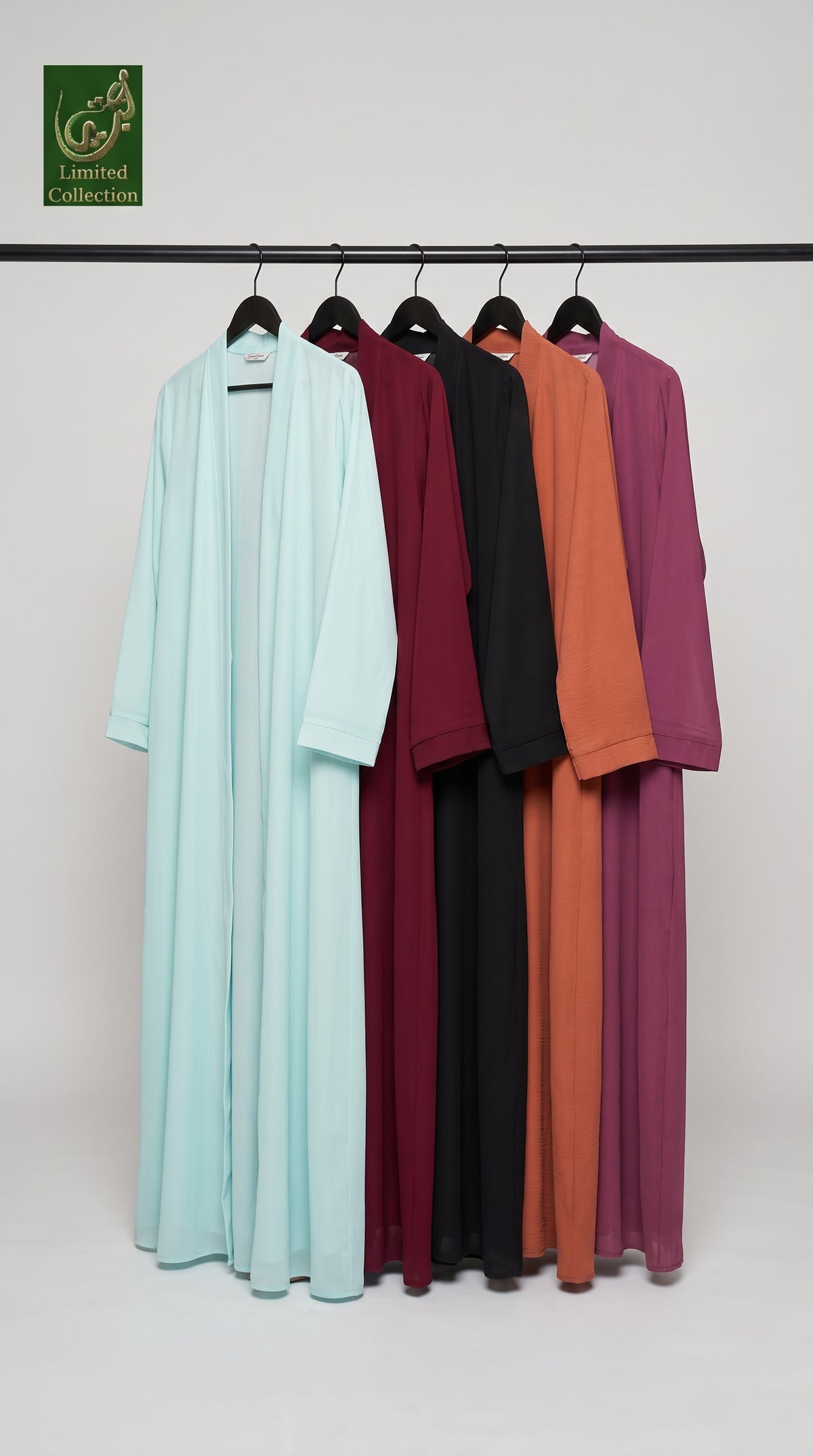 Five long open-front chiffon abaya hanging on a black rack against a plain light gray studio background. The garments are shown in mint blue, burgundy, black, rust orange, and plum purple.