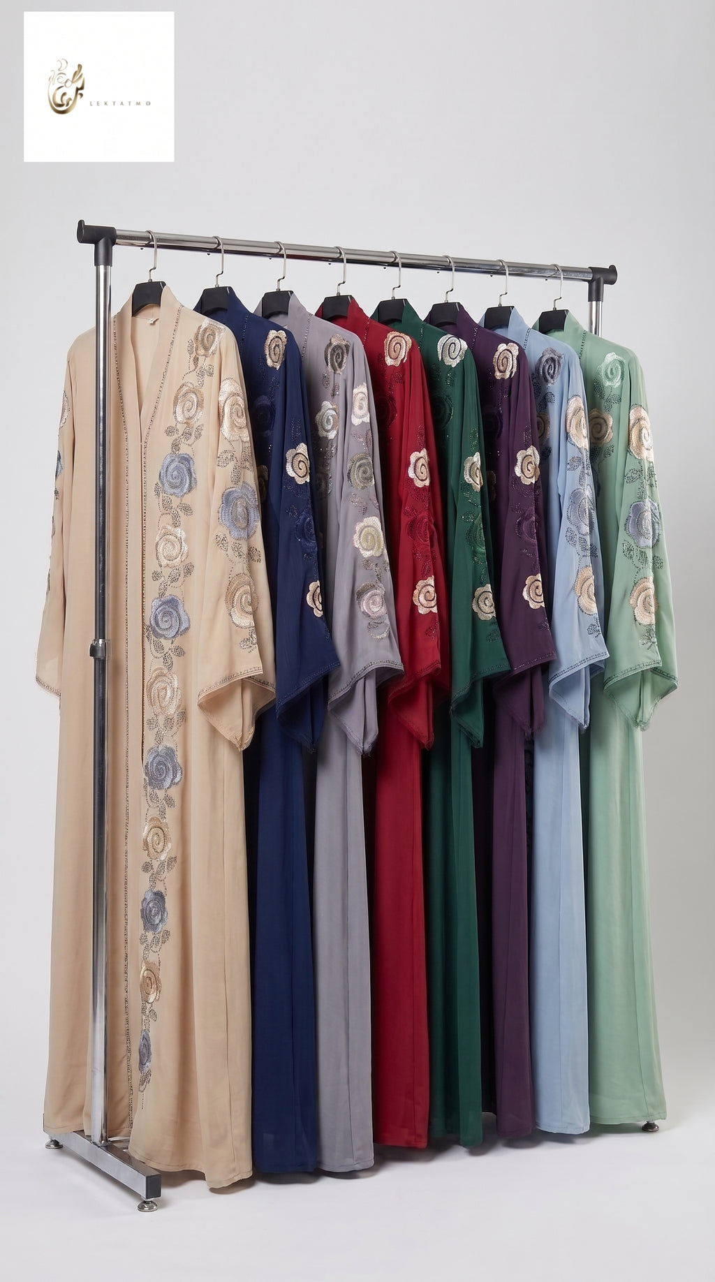 A clothing rack displaying a row of long-sleeved traditional-style front open stone embroidered abayas in multiple colors, including beige, navy, gray, red, green, purple, and light blue, each with floral embroidery on the sleeves and side. The image is set against a plain light gray studio background.