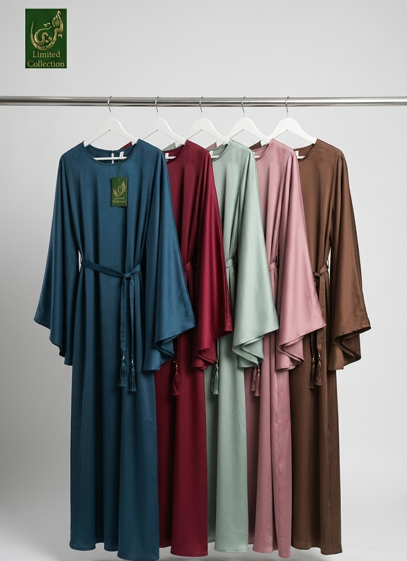 Five long flowing butterfly-style abayas hang on a clothing rack against a light gray studio background. The abayas are shown in blue, burgundy, sage green, dusty pink, and brown.