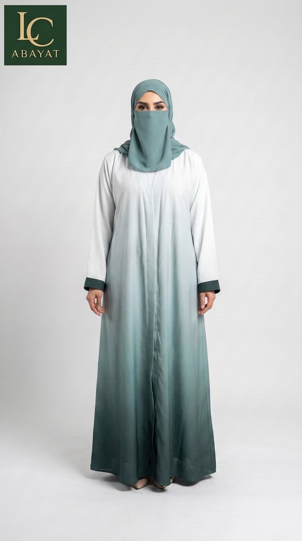 A woman modeling a long modest Front-open ombre abaya with a matching hijab. The dress features a white upper section that fades into a dark teal-green at the bottom, with matching dark green cuffs.