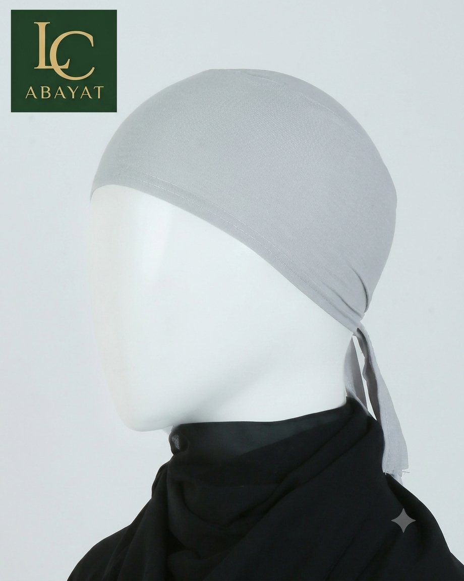 A light gray fabric head covering displayed on a white mannequin head, with a black neck drape underneath. The image includes an LC ABAYAT logo in the top-left corner against a plain light gray background.