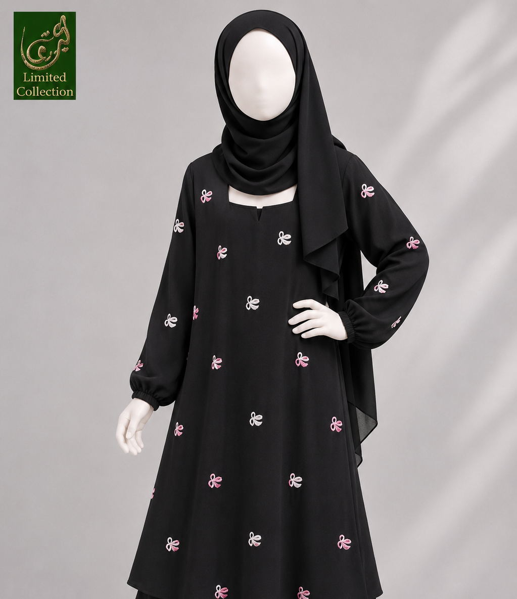 A black long-sleeve modest dress with small pink and white embroidered motifs, shown on a mannequin with a black hijab. A green 'Abayat Limited Collection' logo appears in the top-left corner against a light gray background.