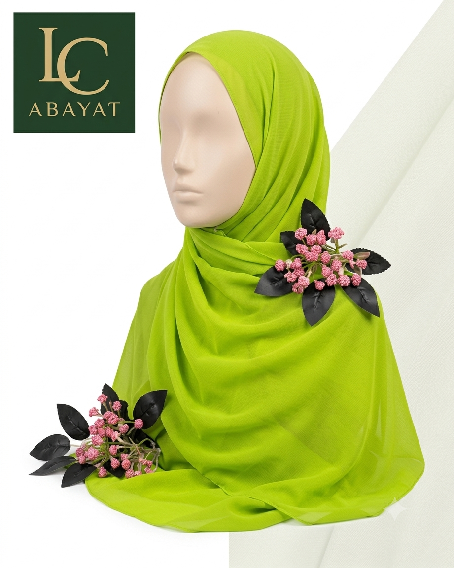 A bright lime green hijab draped on a mannequin head, decorated with two floral hair clips featuring pink berries and black leaves. The logo for 'IC ABAYAT' is visible in the top-left corner.