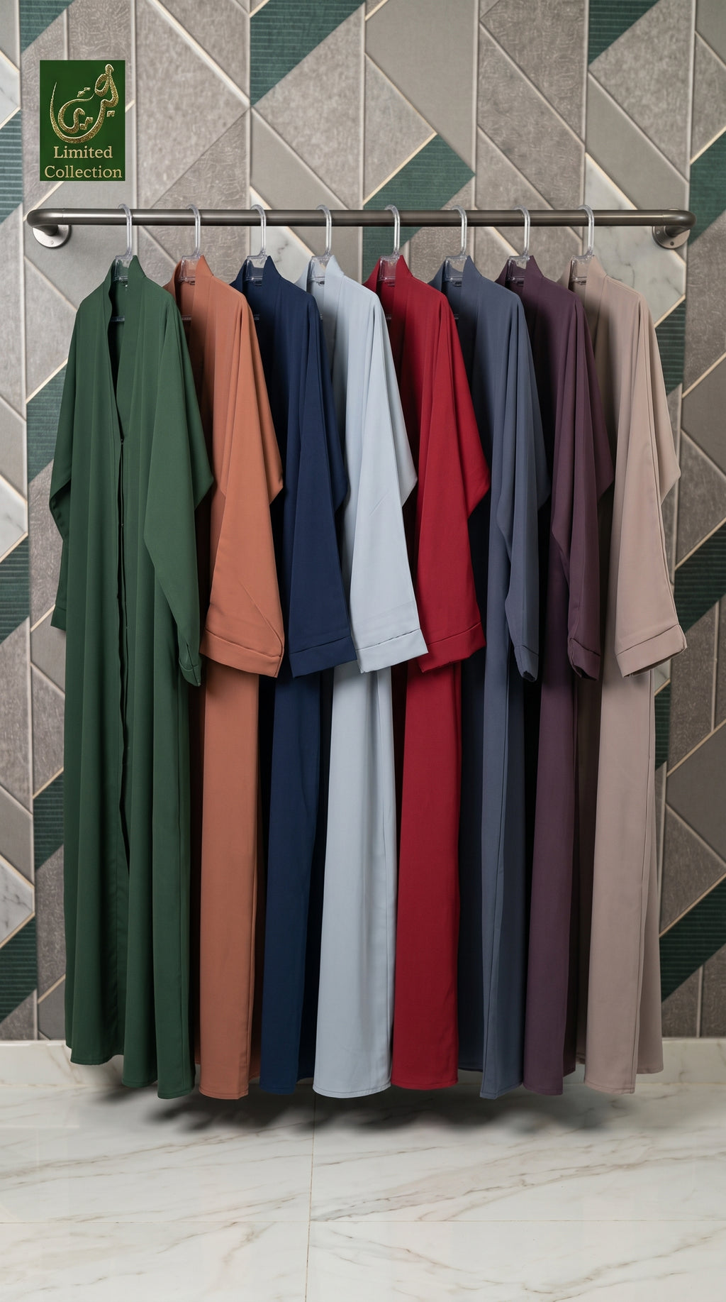 A set of long-sleeve, loose-fitting front-open plain colorful abayas hanging on a metal rack against a geometric tiled wall. The collection features multiple solid colors including green, terracotta, navy, light blue, red, charcoal, purple, and beige.