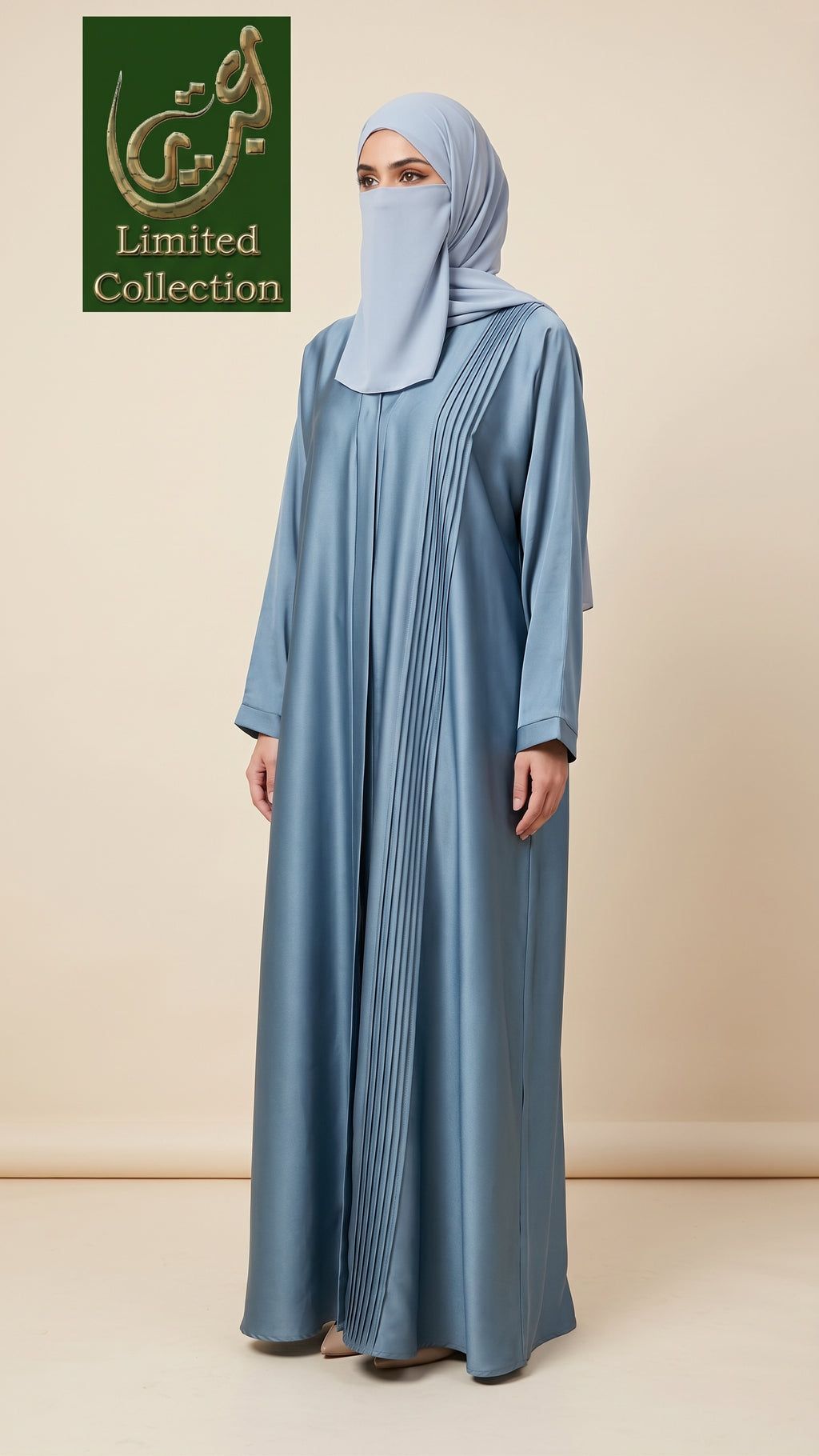 A woman wearing a light blue abaya with vertical pleats and a matching light blue hijab, standing against a beige studio background. A green 'Limited Collection' logo is visible in the top left corner.