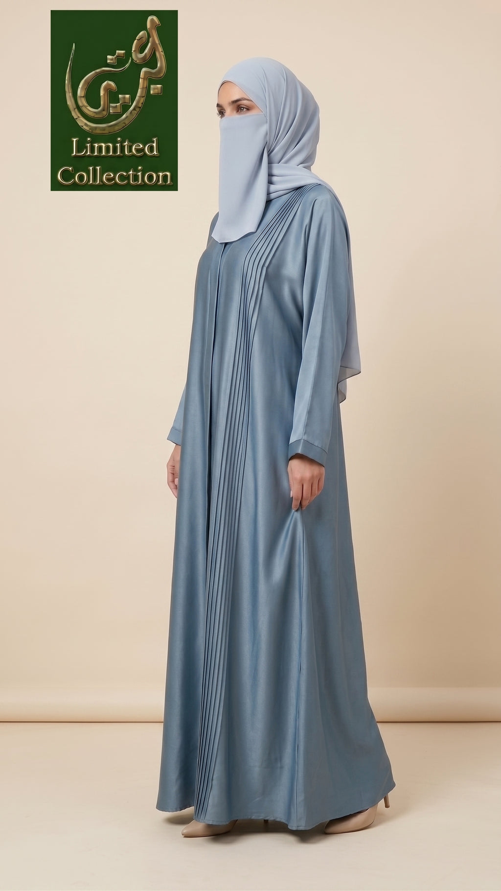 A woman wearing a light blue abaya with vertical pleats and a matching hijab, standing against a beige studio background. A green 'Limited Collection' logo is visible in the top left corner.