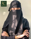 A woman wearing a black niqab and matching black clothing, with her eyes visible through a small side slit. The image has a green 'LC ABAYAT' logo in the top-left corner.