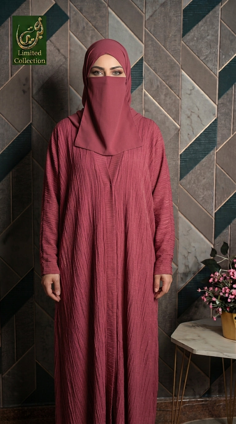 A woman wearing a long, floor-length dusty rose abaya with a matching hijab and face veil, standing in front of a geometric tiled wall. A logo for 'Limited Collection' is visible in the top left corner.