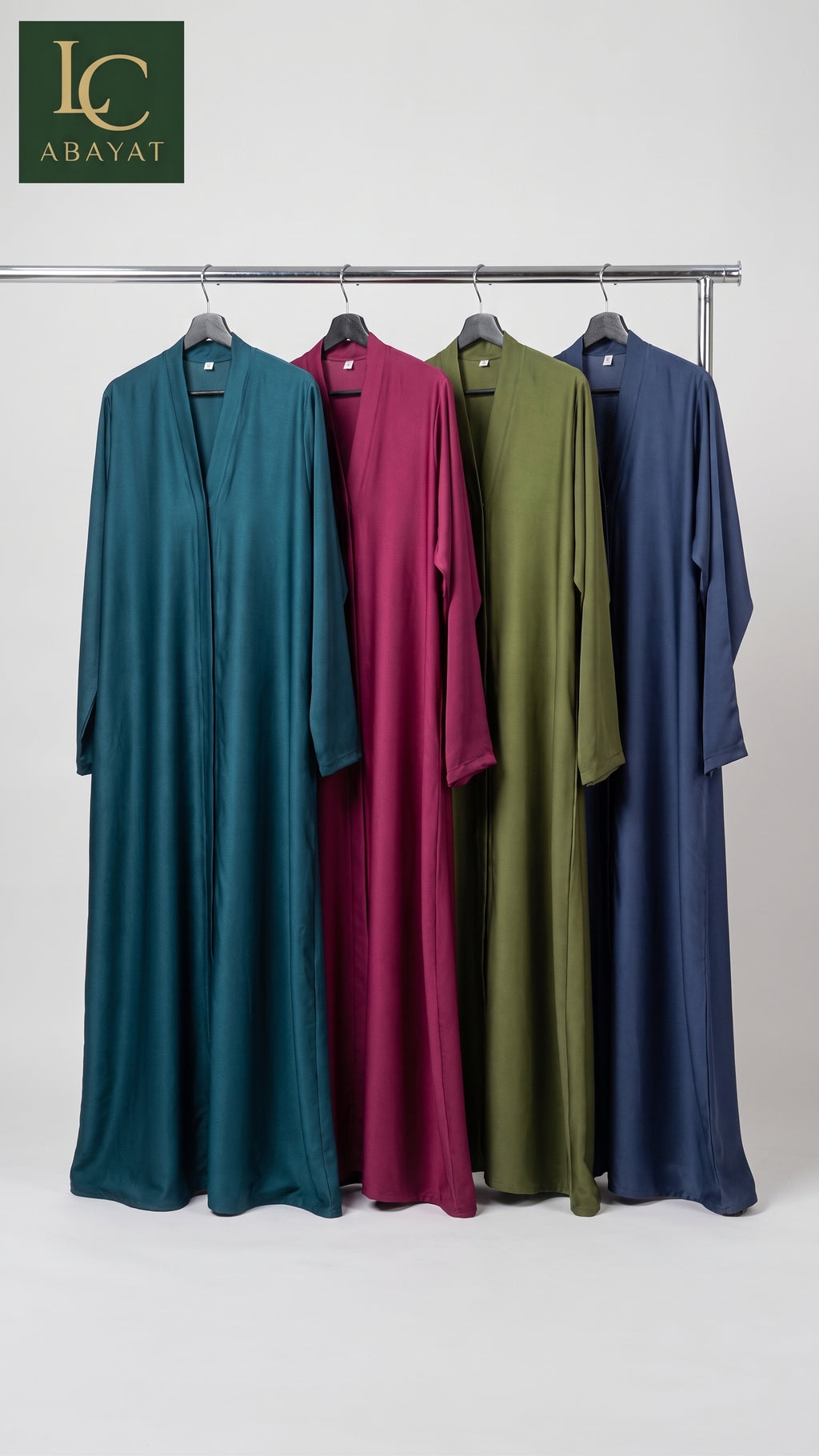 Four long flowing Front-Open Plain Abayas hanging on a metal rack against a light gray studio background. From left to right, the colors are teal, magenta, olive green, and navy blue.