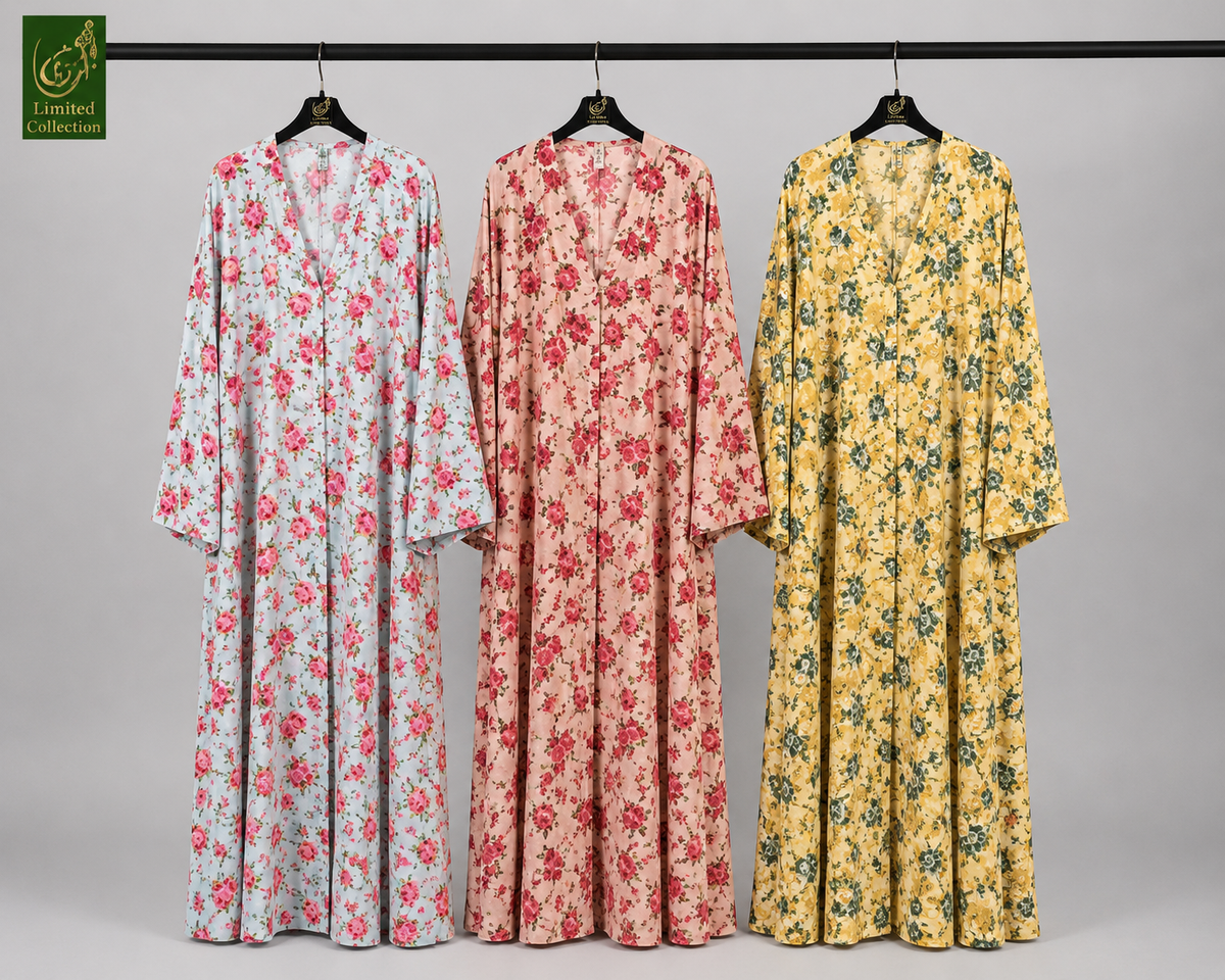 Three long-sleeve floral fornt open abaya hang on black hangers against a light gray studio background. The left gown is white with red and pink floral print, the center gown is peach with red floral print, and the right gown is yellow with blue and green floral print.