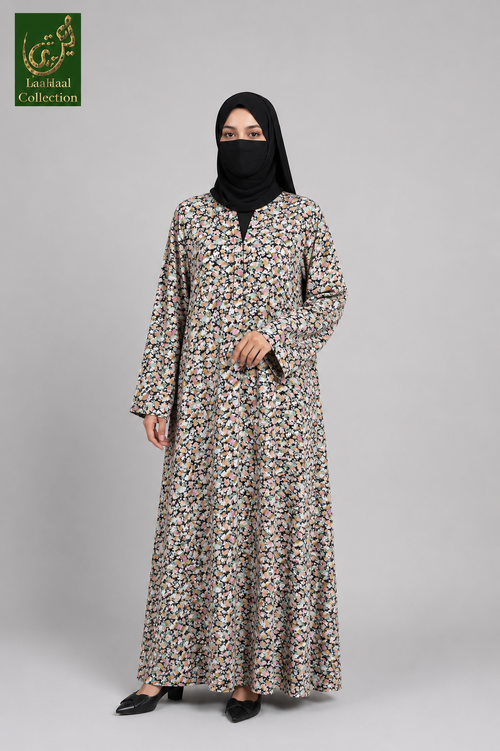 A woman modeling a long-sleeved, floor-length abaya with a dense multicolor floral print on a light beige base, paired with a black hijab and black flats, set against a plain gray studio background.