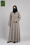 A woman modeling a long-sleeved, floor-length abaya with a dense multicolor floral print on a light beige base, paired with a black hijab and black flats, set against a plain gray studio background.