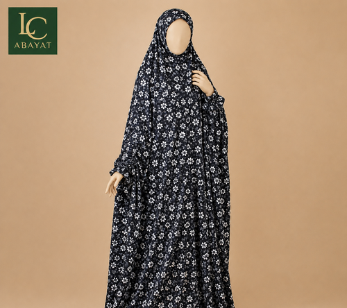 A full-length black modest dress with a white floral pattern, modeled on a mannequin against a solid beige background. The brand logo 'LC ABAYAT' is visible in the top-left corner.