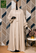 A beige long jilbab dress displayed on a black mannequin set against a geometric patterned wall with a small side table holding flowers. A green 'Limited Collection' logo is visible in the top left corner.