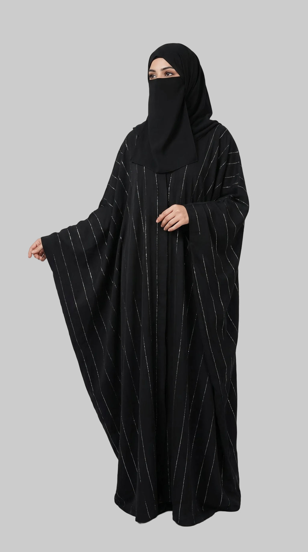 A woman wearing a black abaya with thin vertical metallic stripes and a matching black face covering, standing against a light gray studio background. The brand name LC Abayat  is printed in the top left corner.