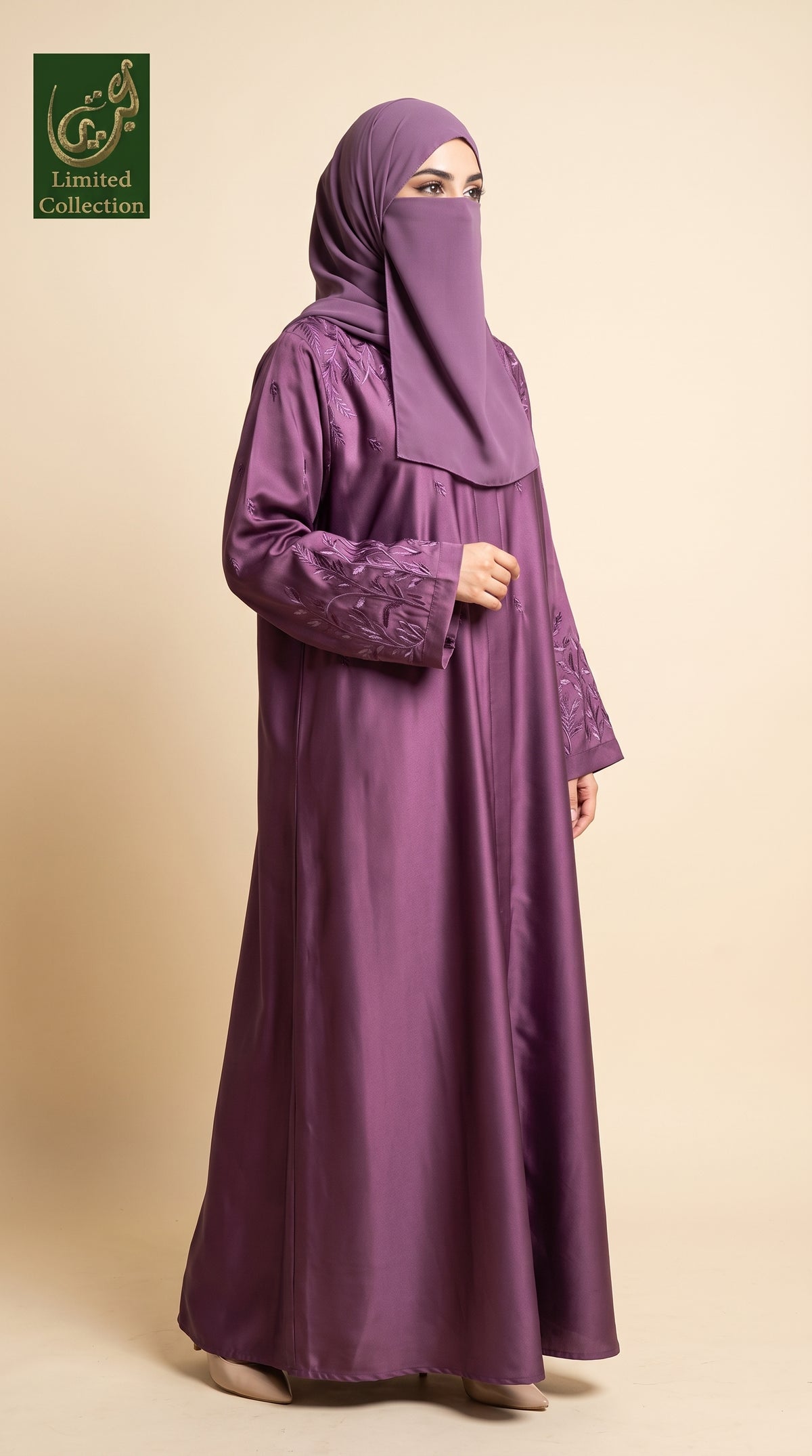 A woman wearing a long, flowing purple abaya with matching embroidered sleeves and a matching hijab, standing against a solid beige studio background. A green 'Limited Collection' logo is visible in the top-left corner.