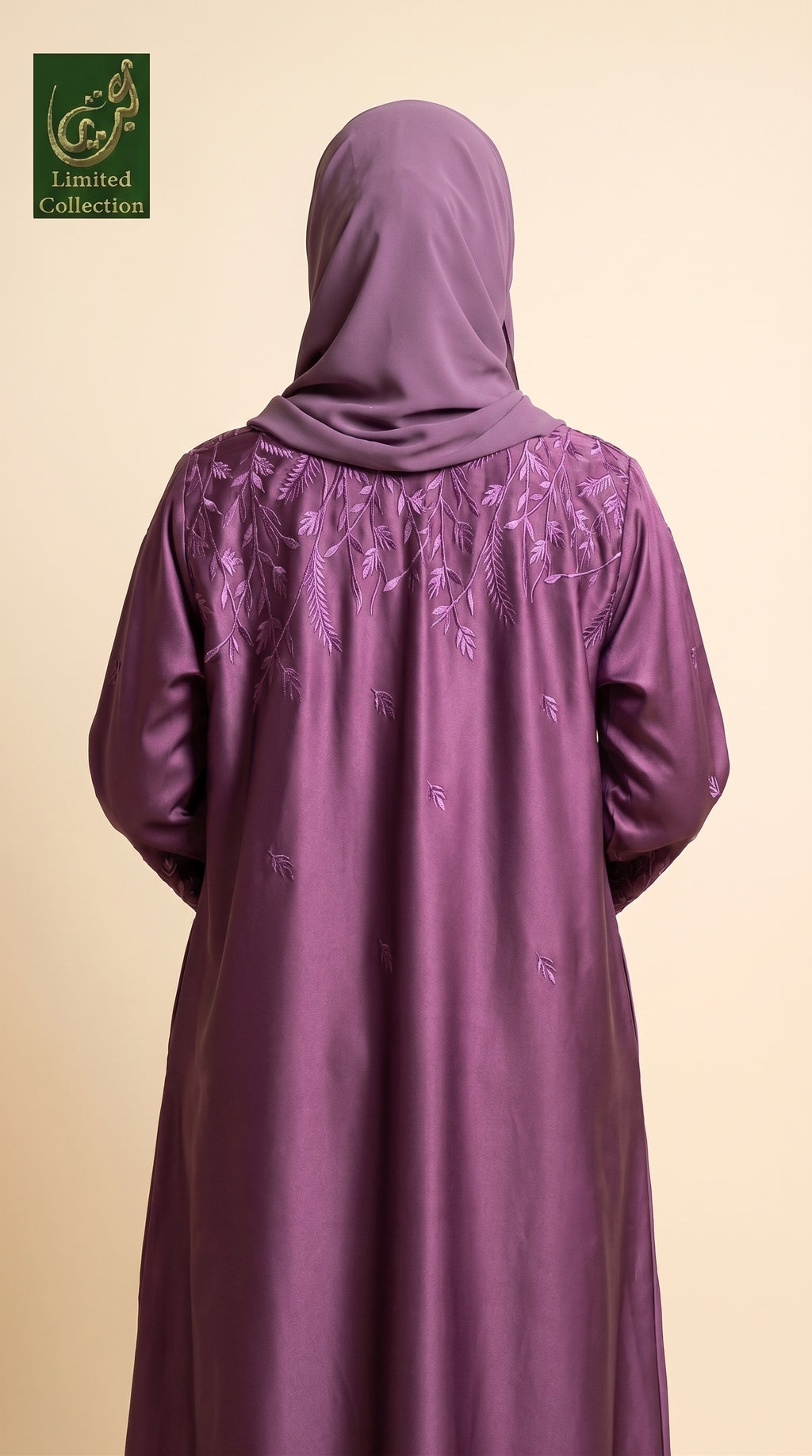 A woman viewed from behind wearing a purple abaya with matching hijab. The abaya features delicate embroidered leaf patterns across the upper back and shoulders.