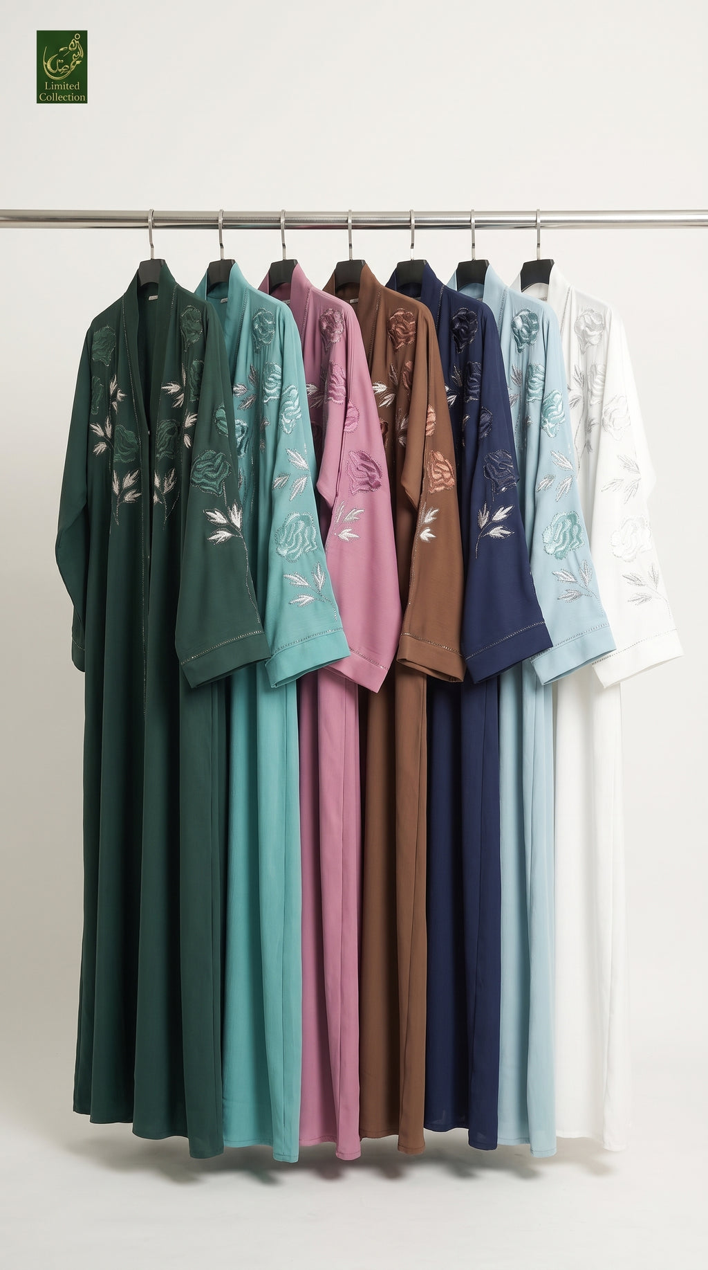 A set of long-sleeved, open-front abayas hanging on a metal rack against a plain light background. The garments come in multiple colors including dark green, teal, pink, brown, navy, light blue, and white, each featuring white floral embroidery on the sleeves.