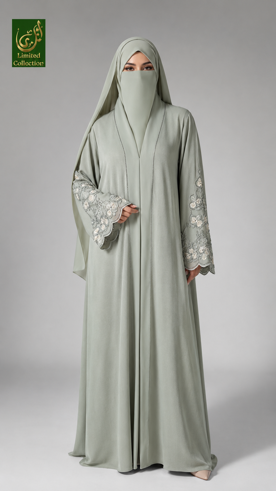 A woman modeling a light sage green abaya with matching hijab and long sleeves featuring white floral embroidery, set against a neutral gray studio background. A 'Abayat Limited Collection' logo is visible in the top-left corner.