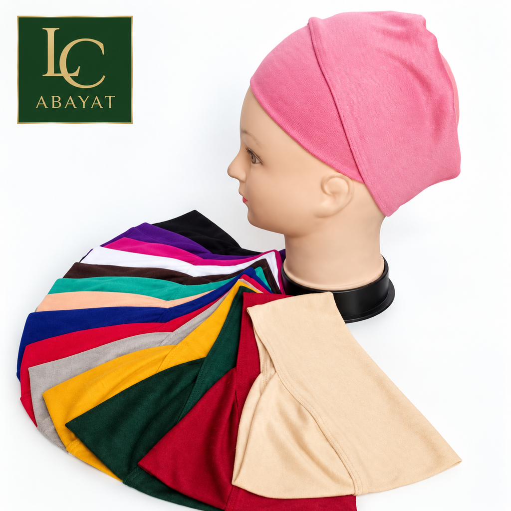 A pink fabric hijab tube band displayed on a mannequin head, with a hijab cap of multiple fabric color swatches spread in front. The Abayat logo is visible in the top-left corner.