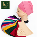 A pink fabric hijab tube band displayed on a mannequin head, with a hijab cap of multiple fabric color swatches spread in front. The Abayat logo is visible in the top-left corner.